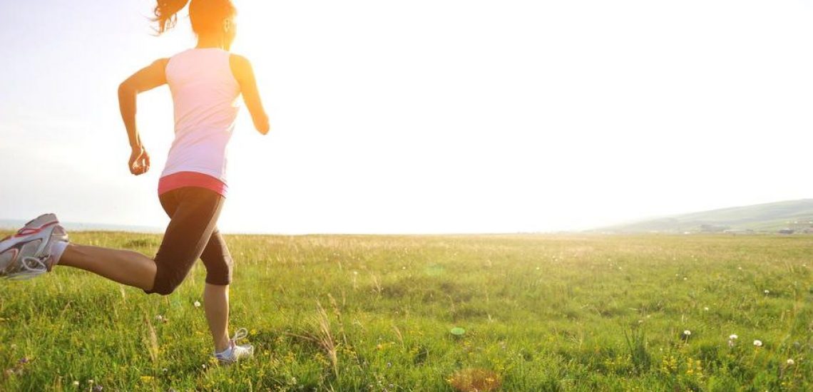 Runner athlete running on grass seaside. woman fitness sunrise/sunset jogging workout wellness concept.